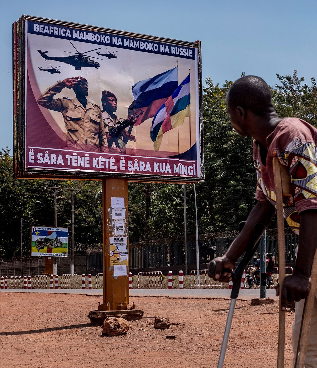 A man with crutches looks at a large bilboard sign proclaiming collaboration between Russian and the Central African military in downtown Bangui, Central African Republic