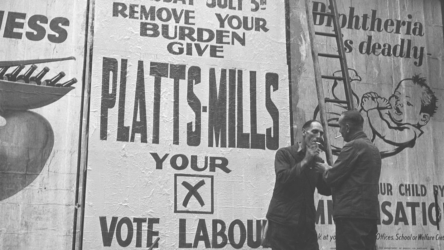 Two bill posters enjoy a cigarette break after pasting up a campaign billboard poster for John Platts-Mills, the Labour Party candidate for the north London constituency of Finsbury, on 20th June 1945. John Platts-Mills would go on to win the seat for the Labour Party in the upcoming 1945 United Kingdom general election. (Photo by Konig/Popperfoto via Getty Images)