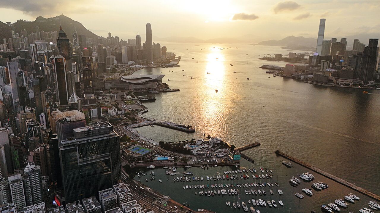 An aerial photo shows a view of Hong Kong Island and Victoria Harbour at sunset.