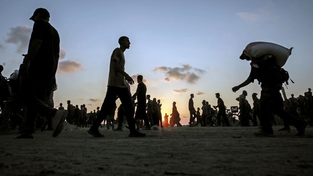 Palestinians gather to collect sacks of flour from an aid distribution point in Beit Lahia, northern Gaza