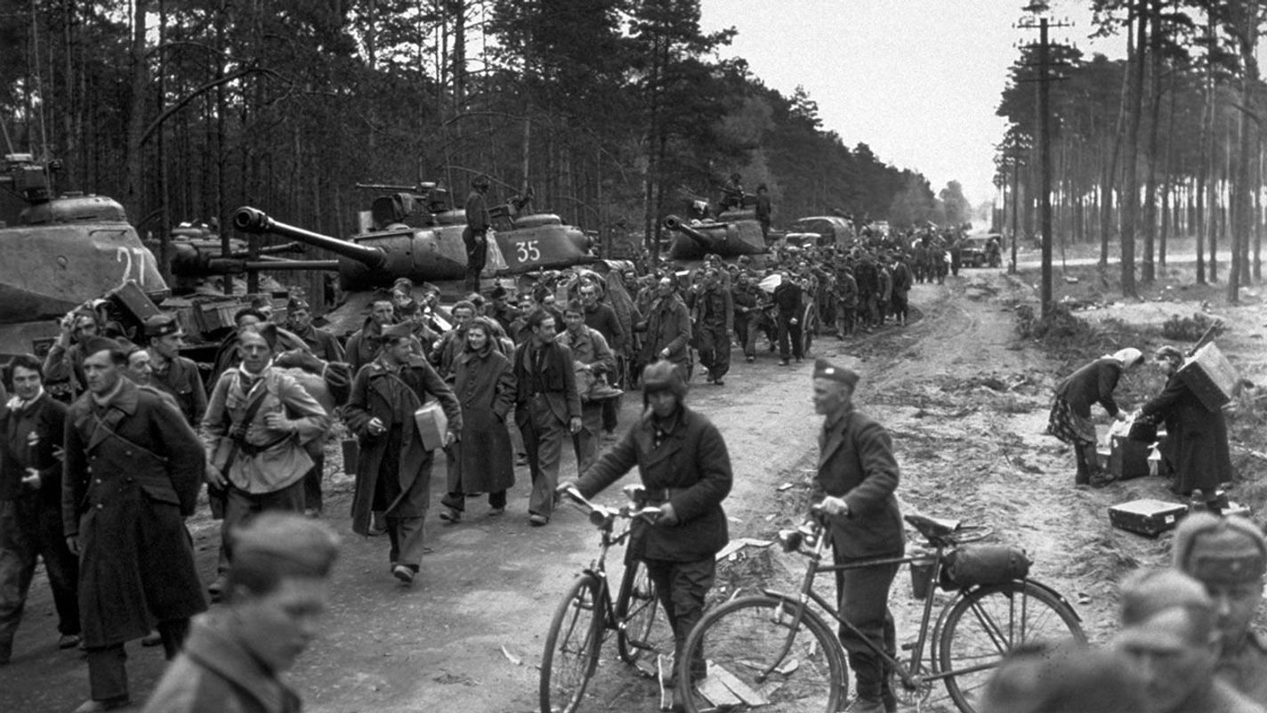 1945: Liberated French prisoners on a road, west of Berlin, passing by a Russian Stalin tanks which had travelled 2,000 miles during the course of the war.