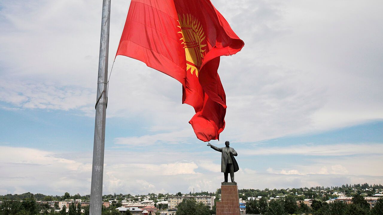 The Kyrgyz national flag flies at half staff in front of the statue of of the Soviet founder Vladimir Lenin on a central square in the southern Kyrgyz city of Osh