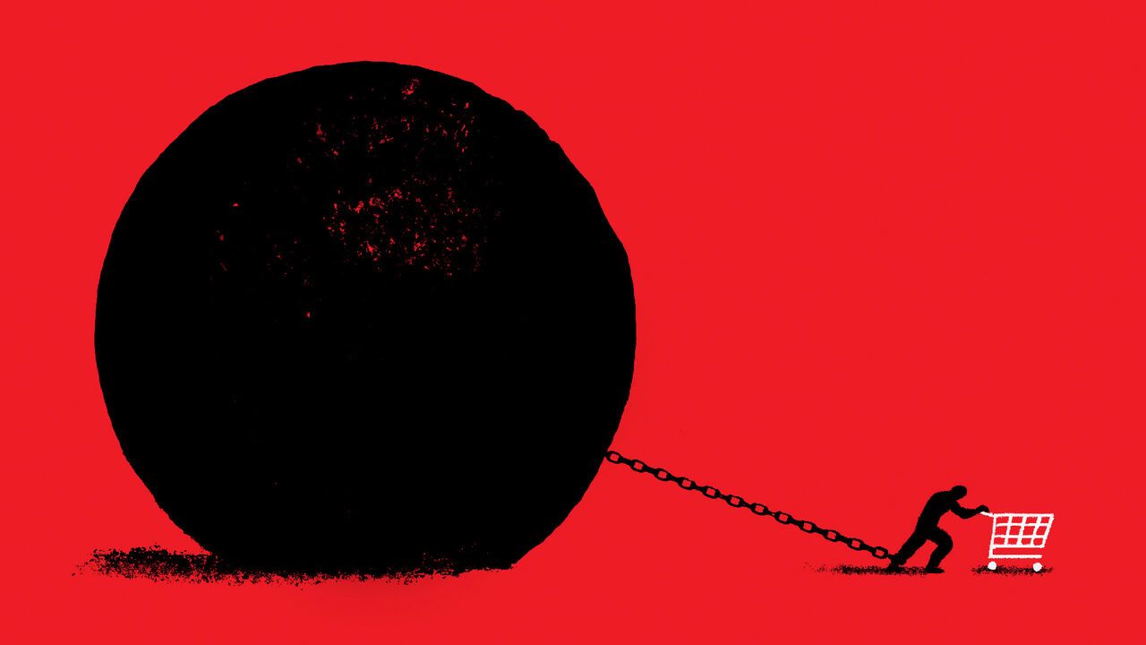 A person pushing a shopping cart , held back by a giant ball and chain